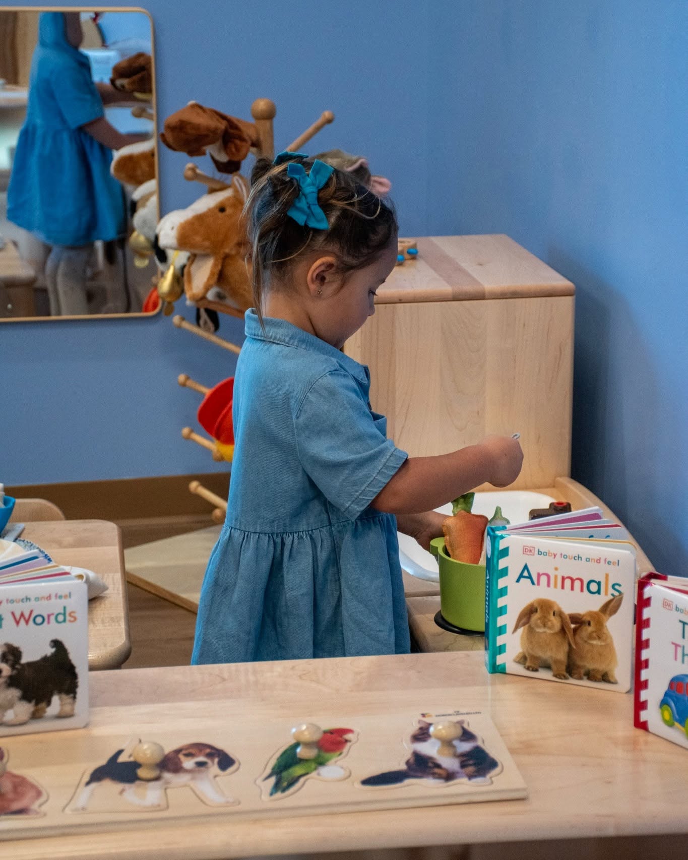 Child playing with toy kitchen set near books and animal puzzle