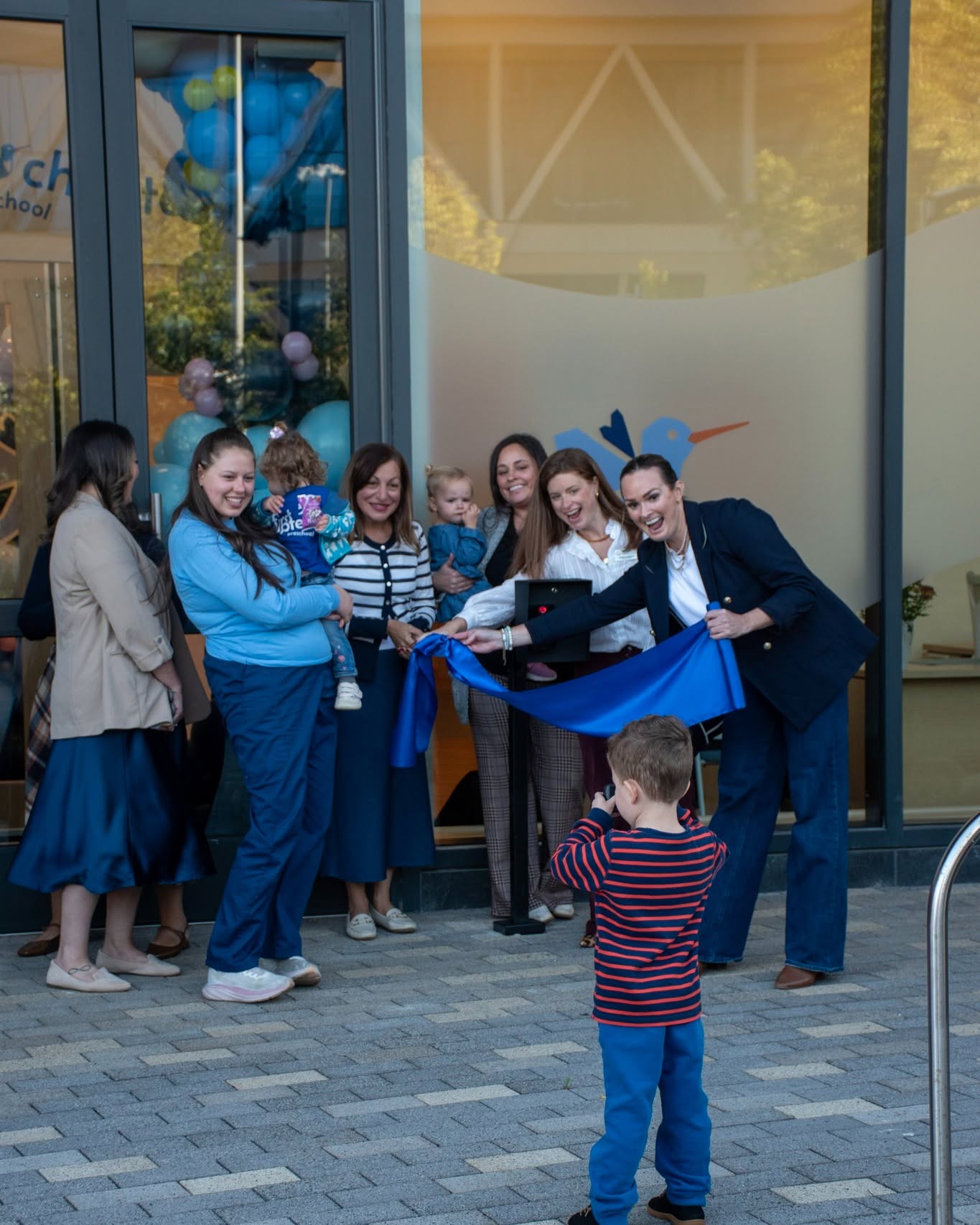Group of people cutting a blue ribbon at an entrance