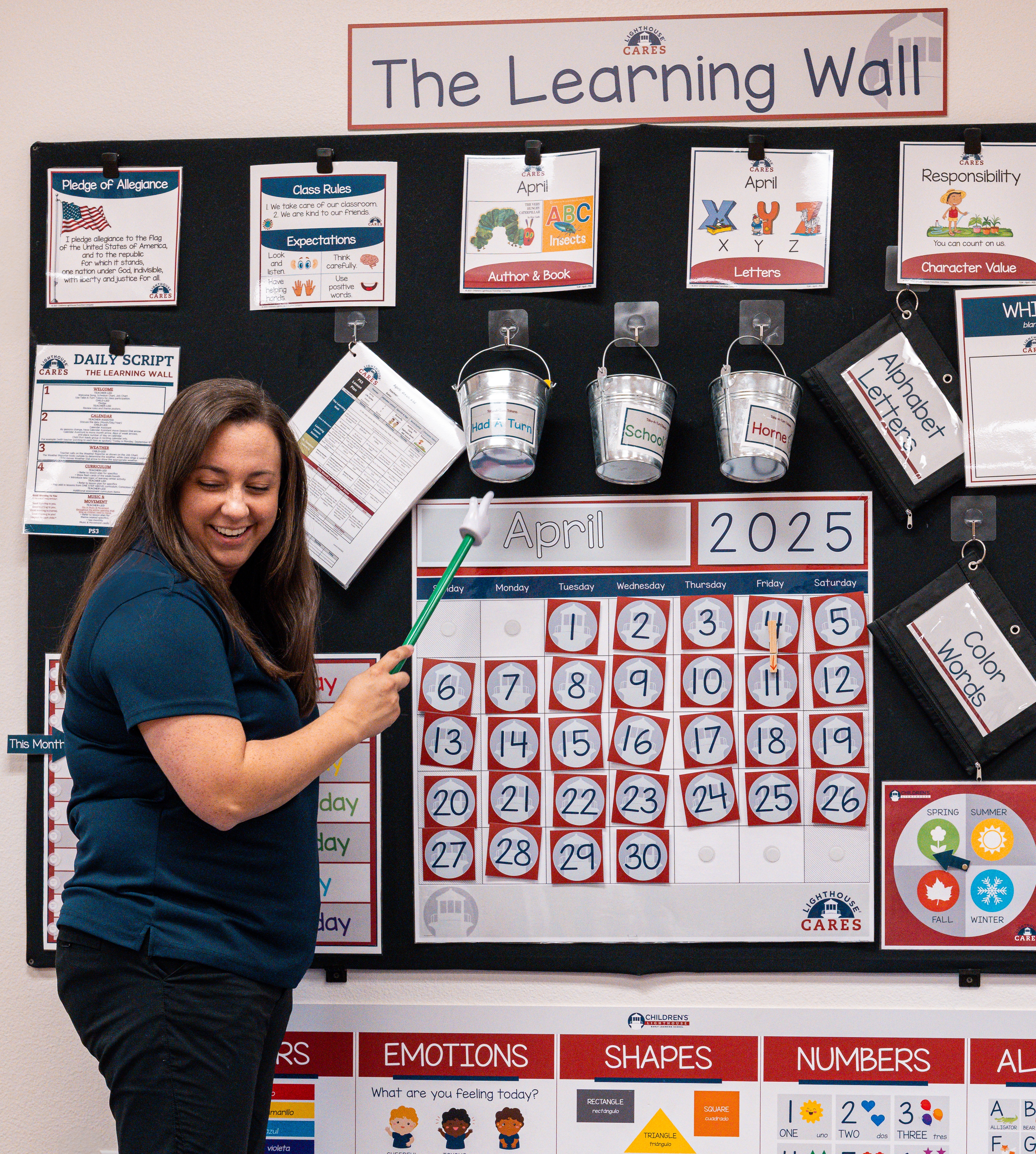 Teacher pointing at a calendar on a learning wall in a classroom