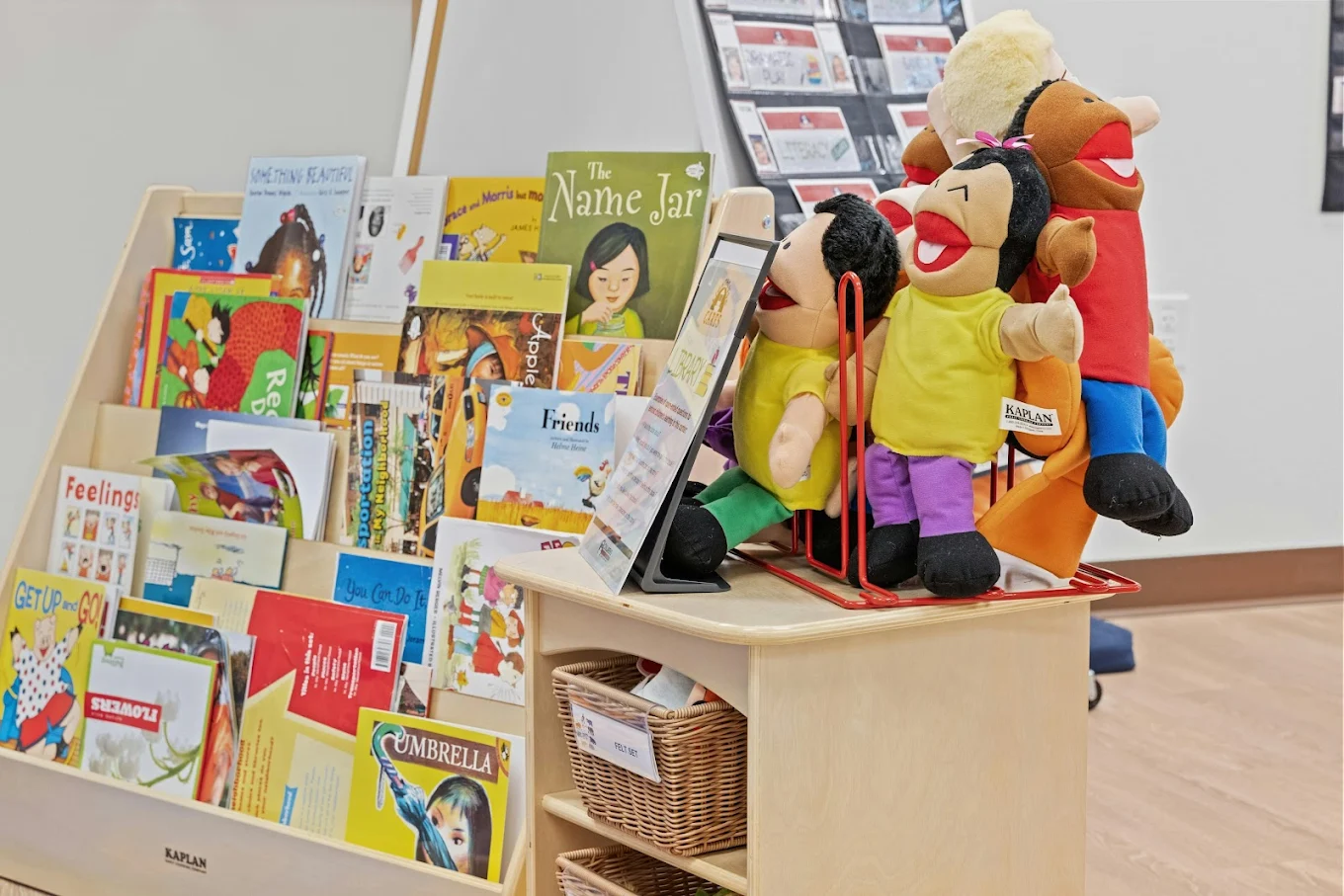 A wooden shelf filled with children's books and a stand of hand puppets