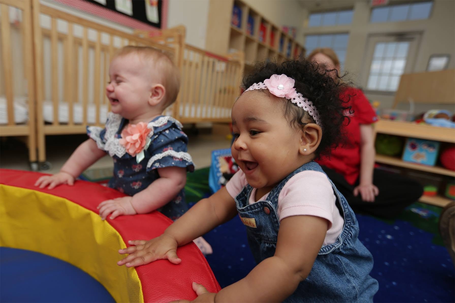 Two children standing at a padded play partition in a classroom