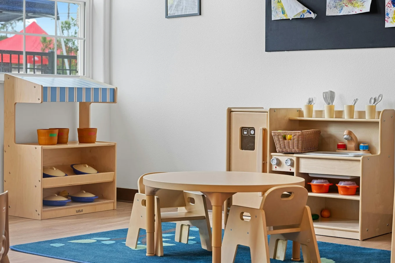 Wooden toy kitchen set with table and chairs in a classroom play area