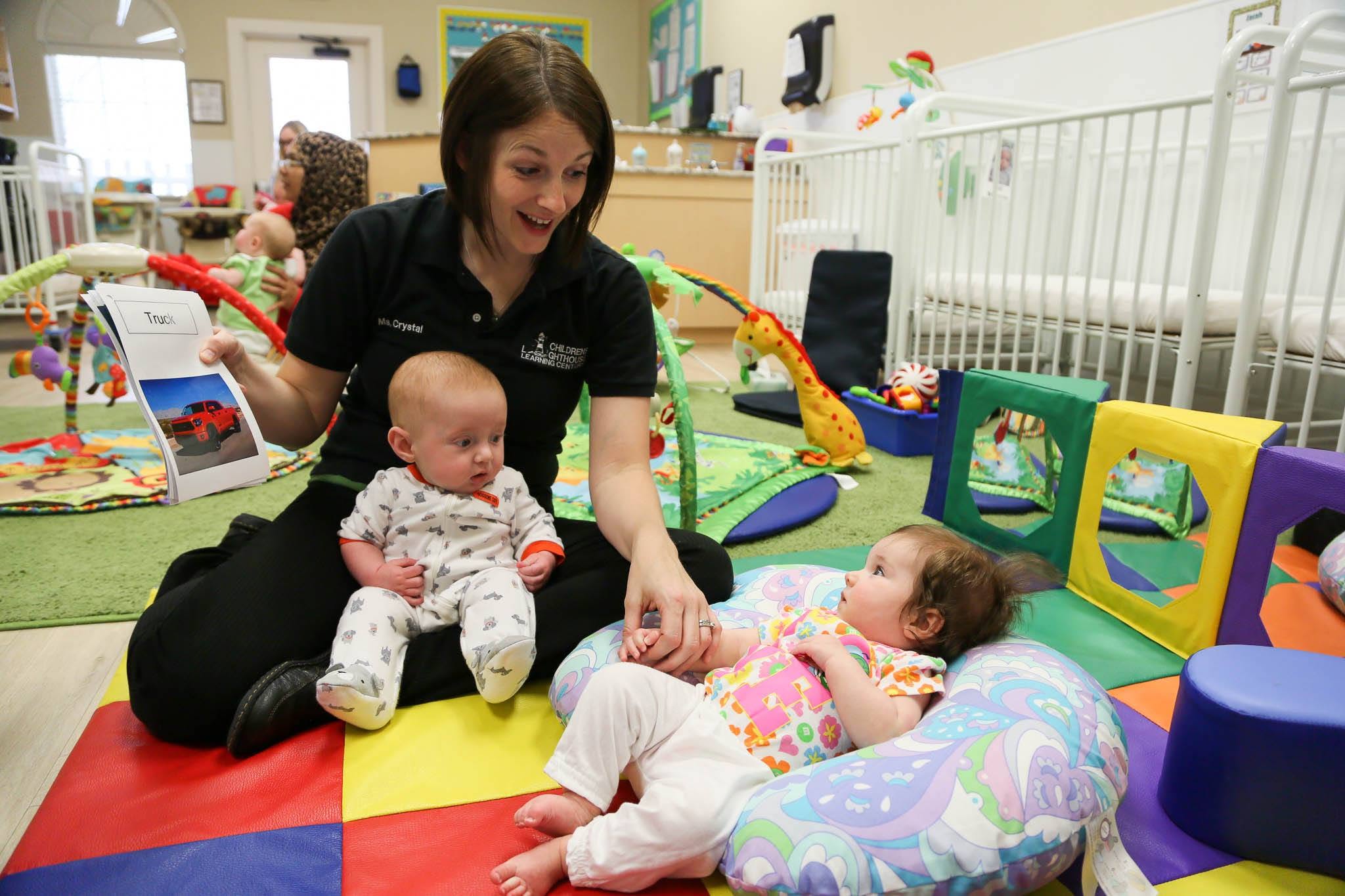 Adult showing a book to two infants in a daycare setting