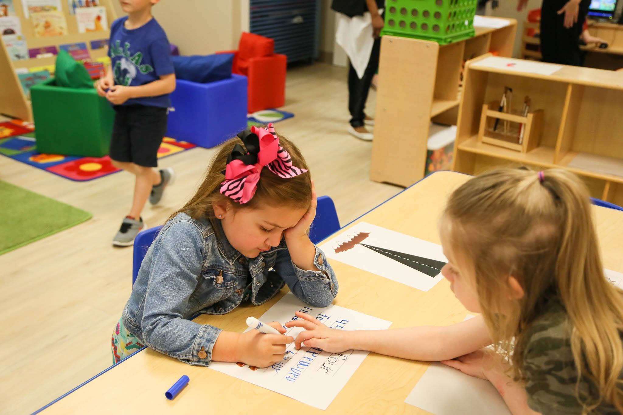 Two children working on worksheets at a classroom table