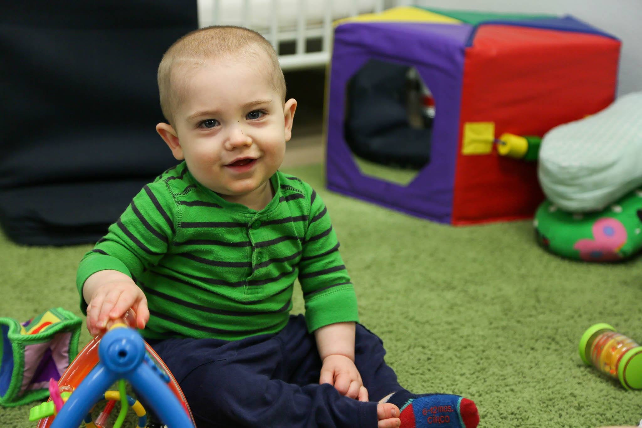 A child playing on a green mat with toys