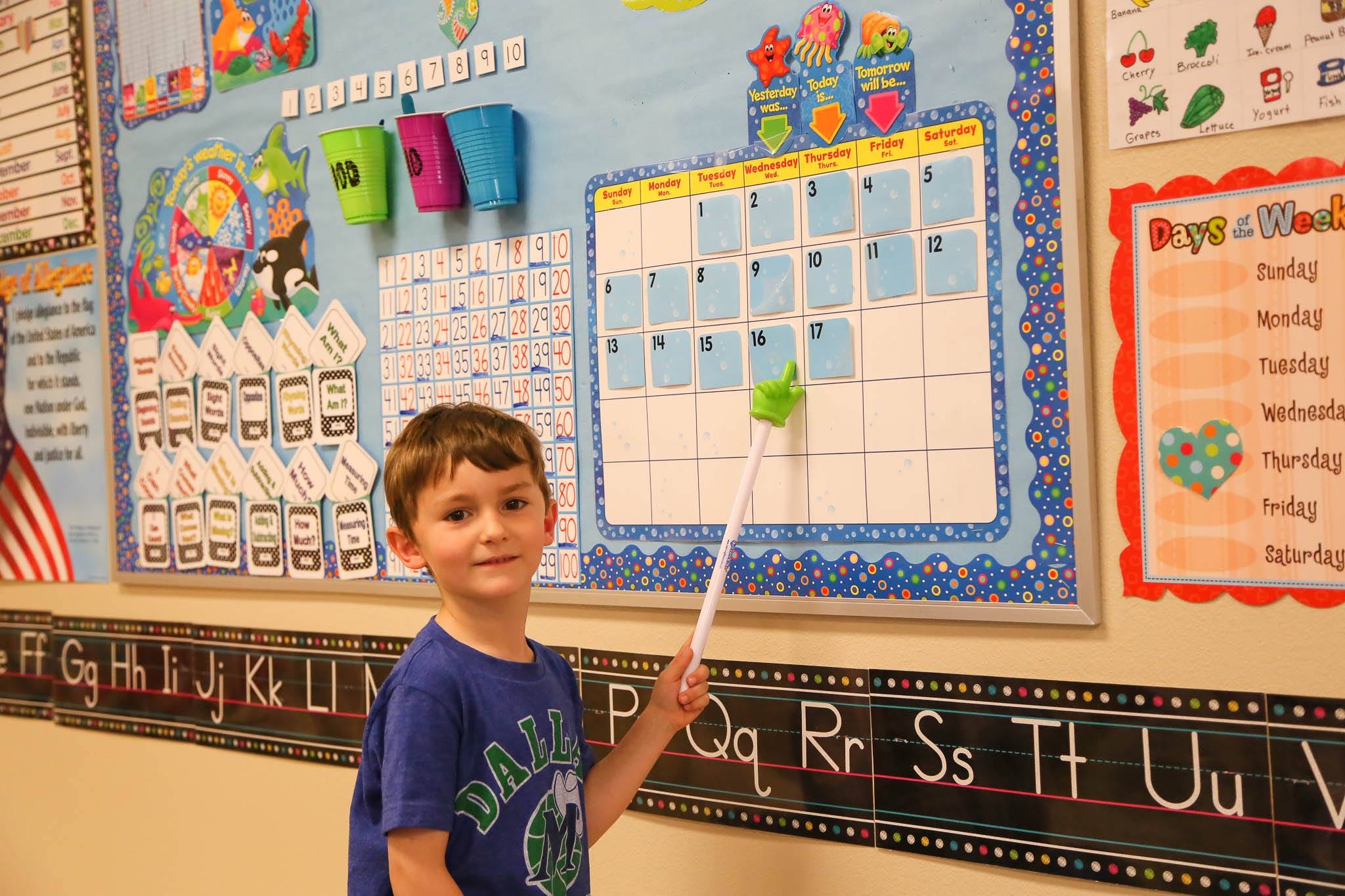 Child pointing at a calendar in a classroom