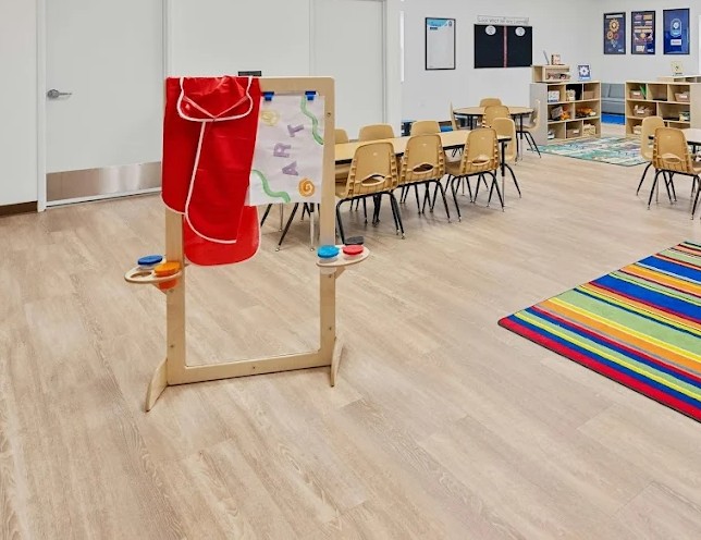 Wooden art easel with paint supplies in a classroom