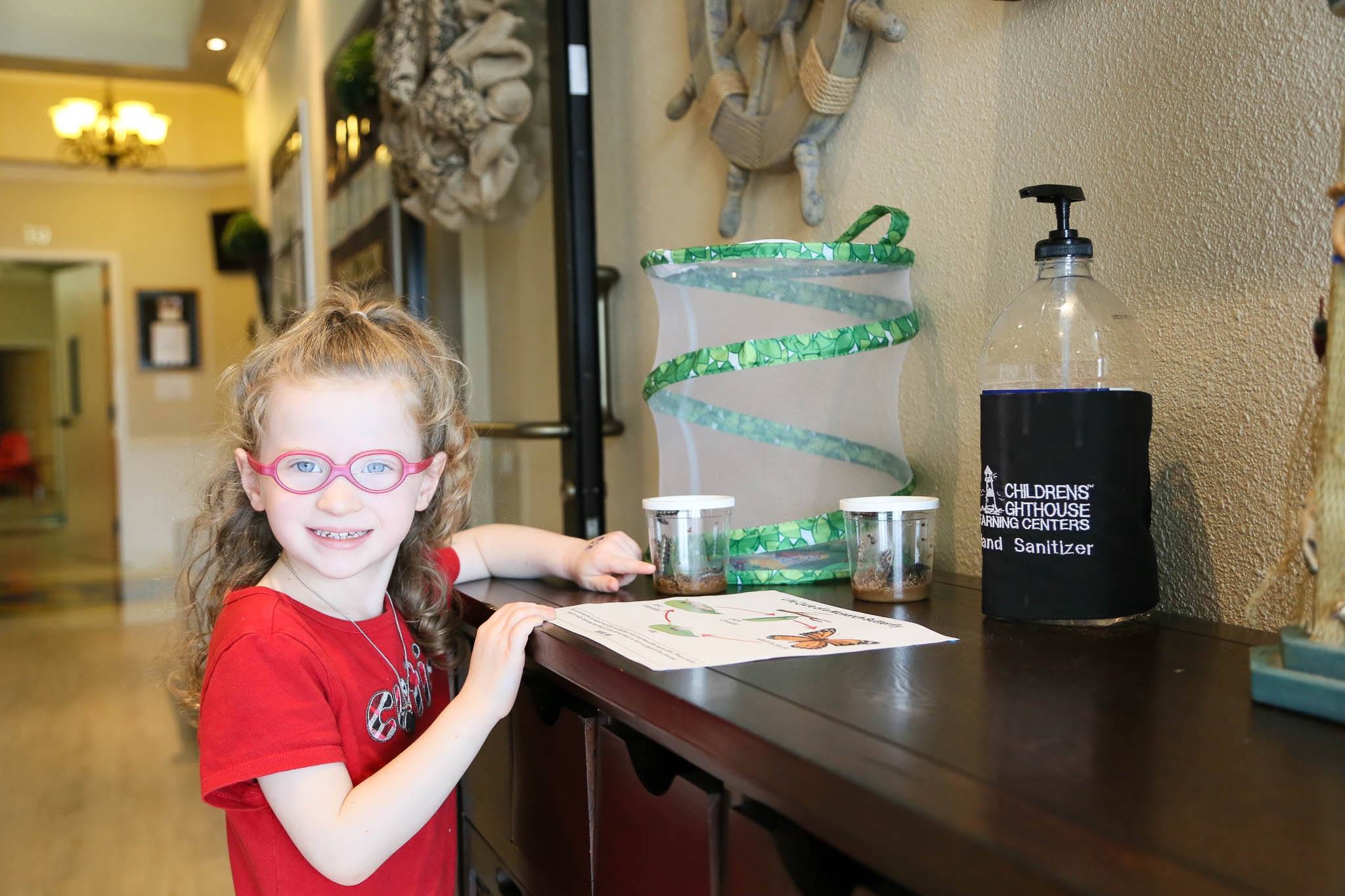 Child observing caterpillars in a classroom