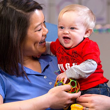 Adult holding a child who is holding a toy