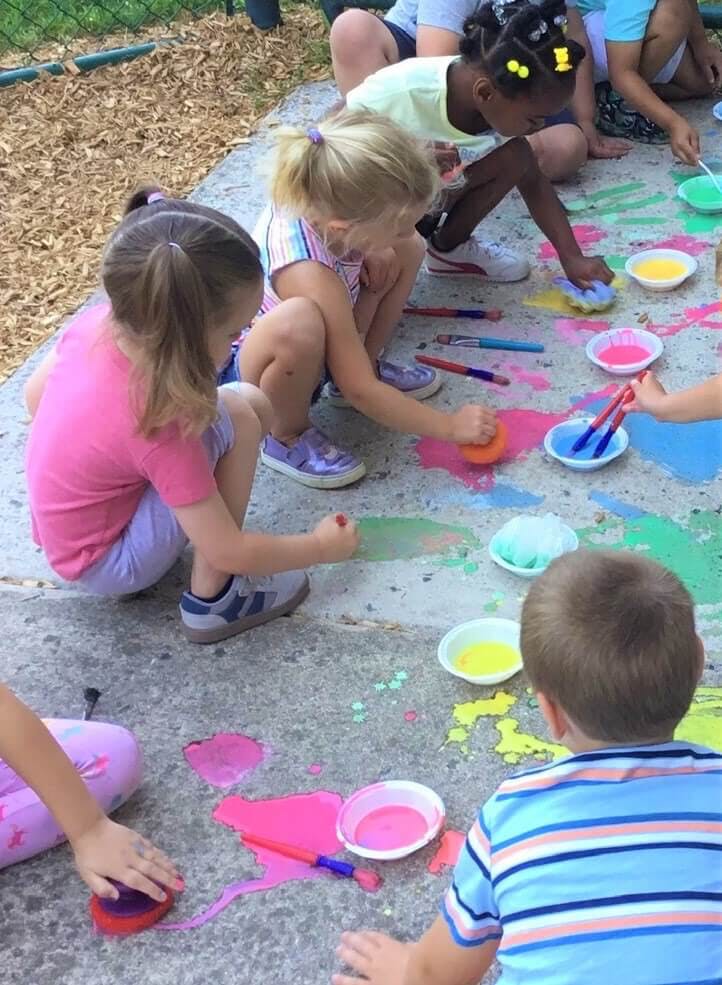 Children painting on the ground with colorful paints