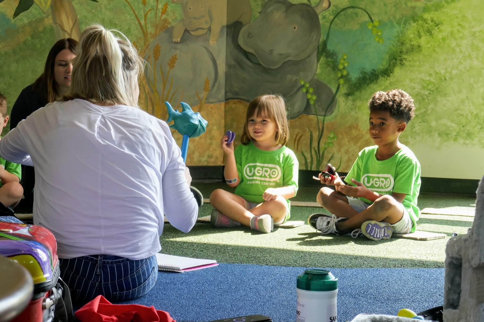 Adult and two children sitting on the floor in a classroom