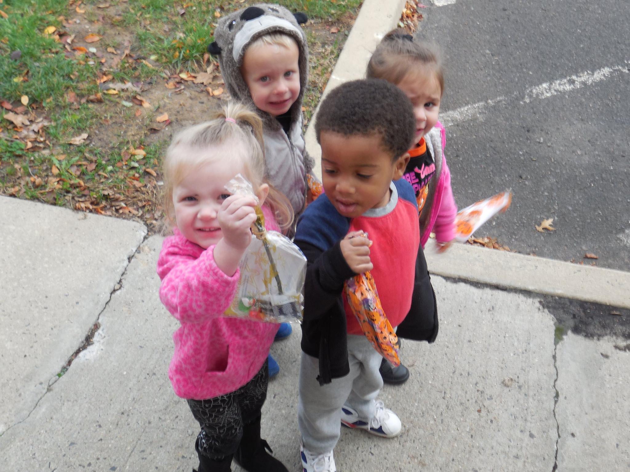 Four children holding bags on a sidewalk