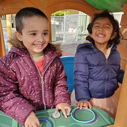Two children in winter coats playing