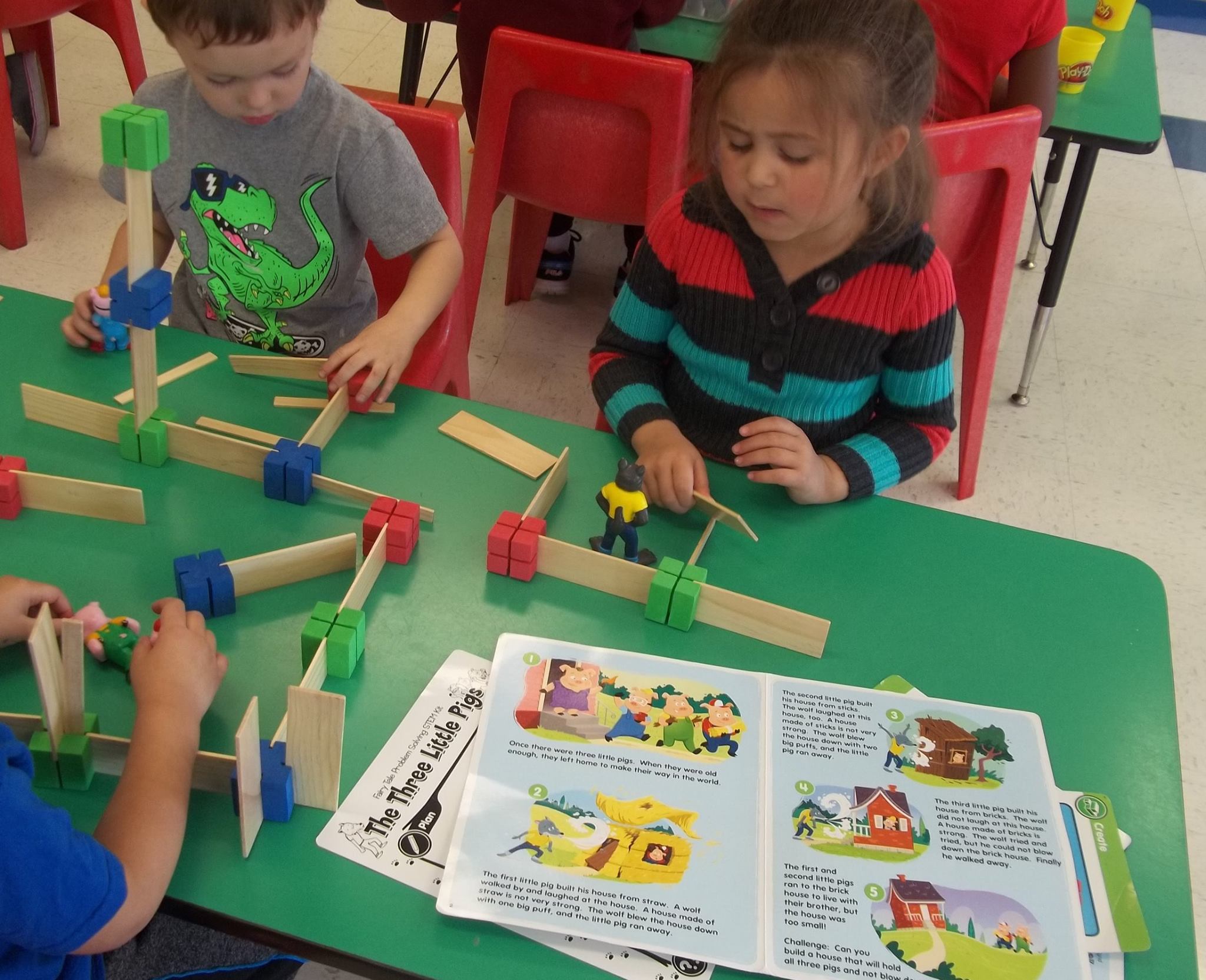 Children playing with building blocks and looking at a book