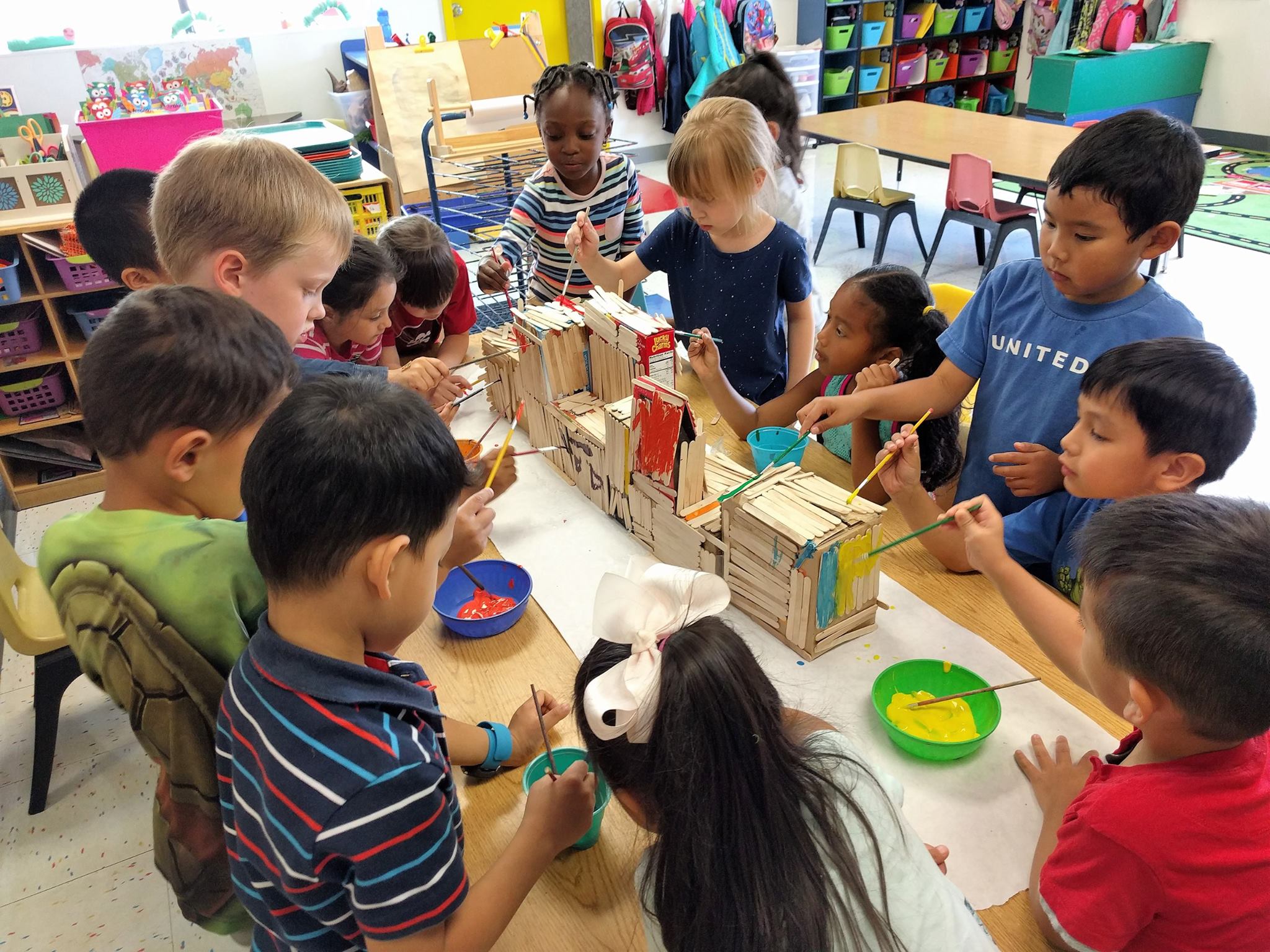 Children painting craft stick structures in a classroom