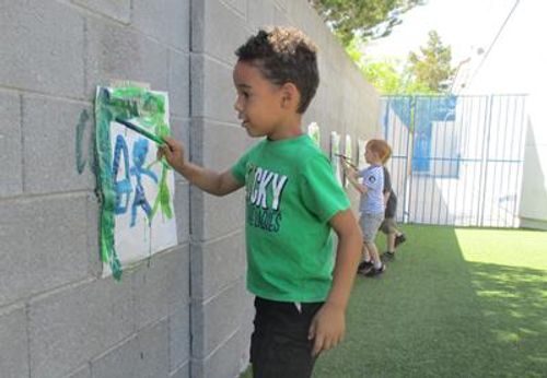 Child painting on a wall outdoors