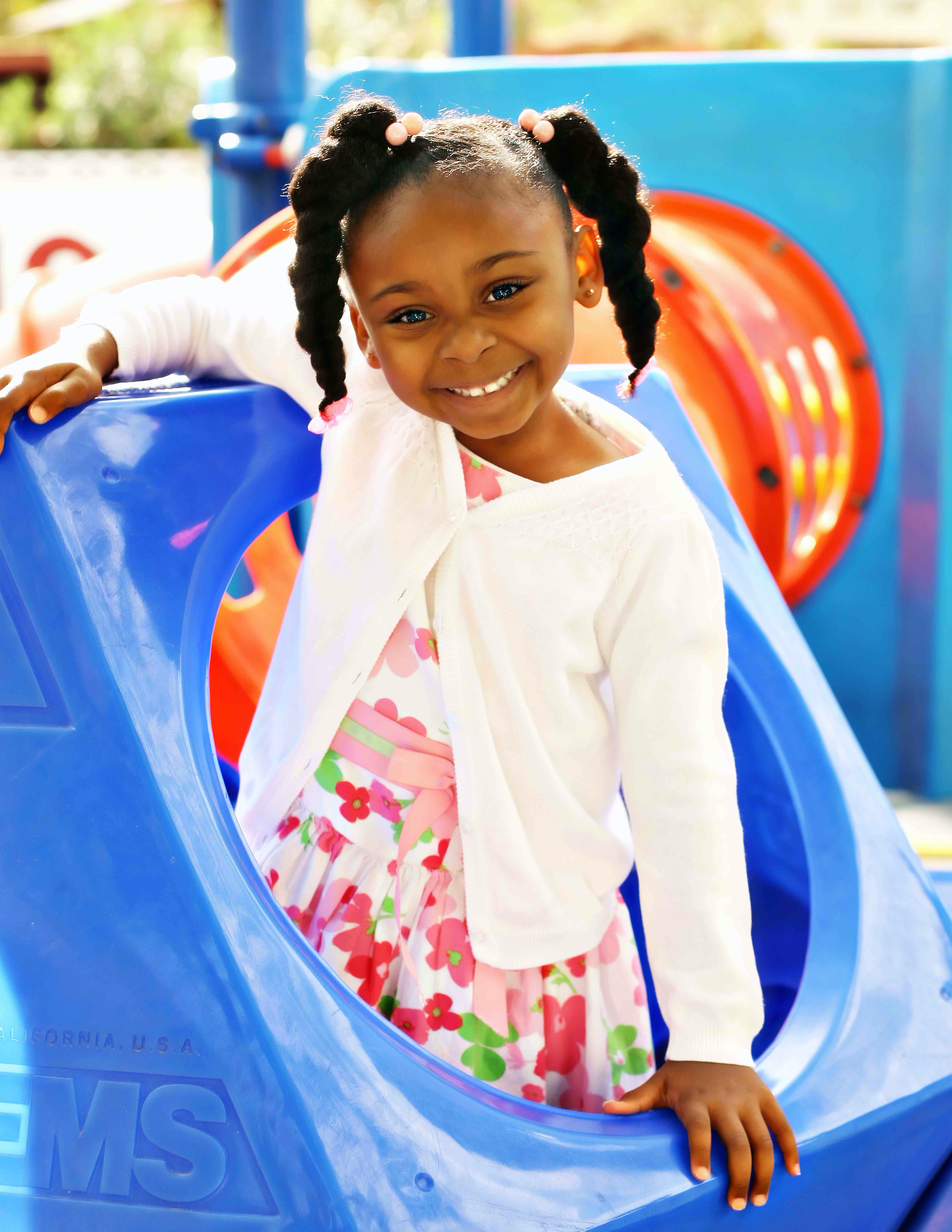Child in pigtails on a blue playground structure