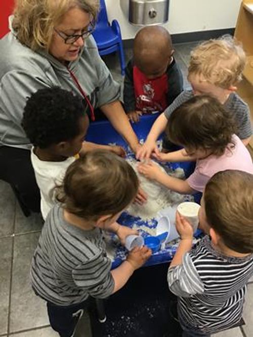 Adult and multiple children playing with sensory bin