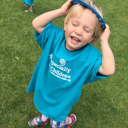 Child in a blue shirt holding a blue tambourine on their head