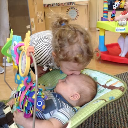 Child kissing a baby on the forehead