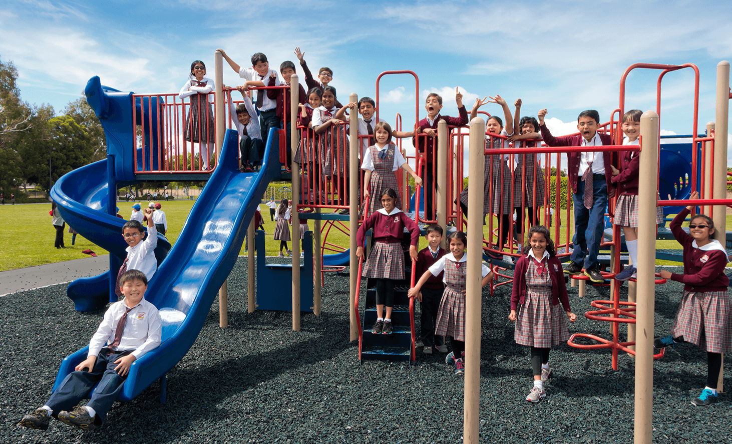 Children playing on a playground structure with slides and climbing structures