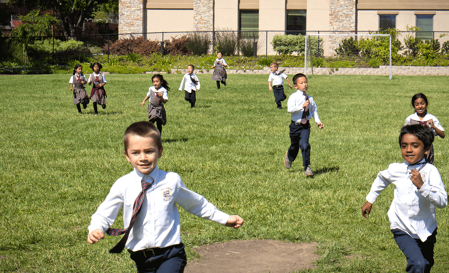 Children in uniforms running on a grassy field