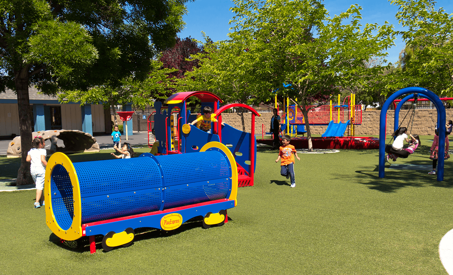 Children playing on a playground with a blue tunnel and swings