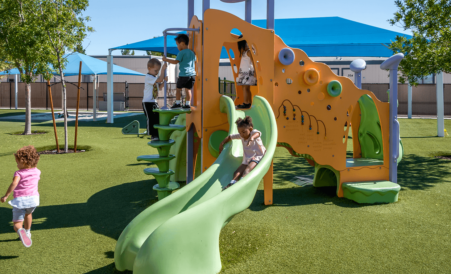 Children playing on a playground slide and climbing structure