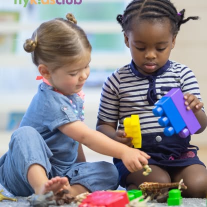 Two children playing with building blocks and toys on the floor