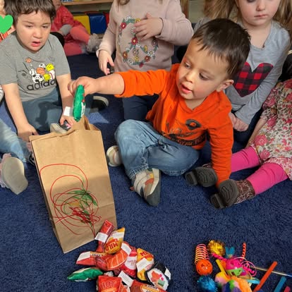 Child reaching into a brown paper bag with other children around