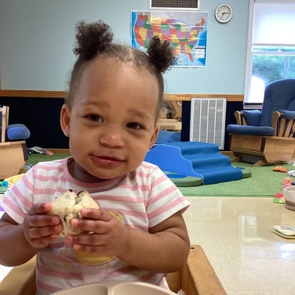 Child in a high chair holding a muffin