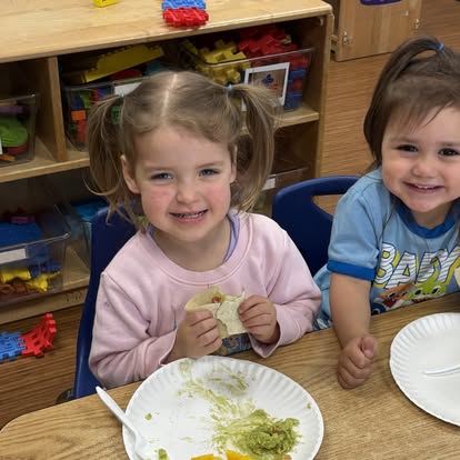 Two children sitting at a table with plates of food