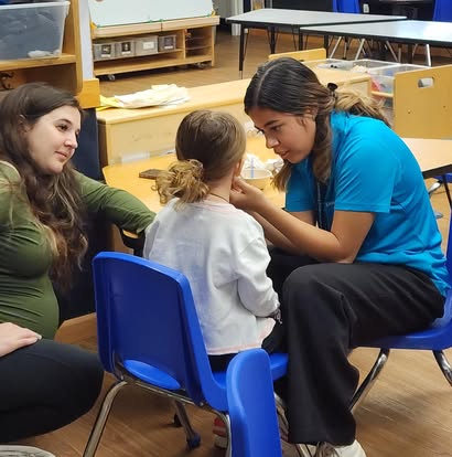 Two people interacting with a child in a classroom