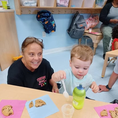 Adult and child at a table with cookies and a drink