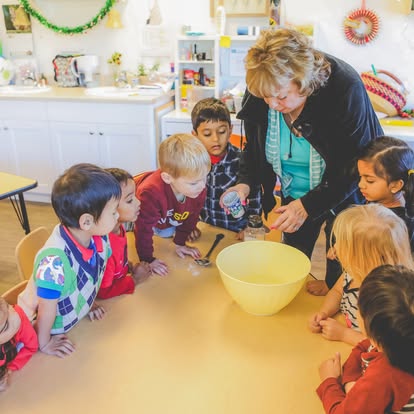 Adult leading a group of children in a science experiment at a table