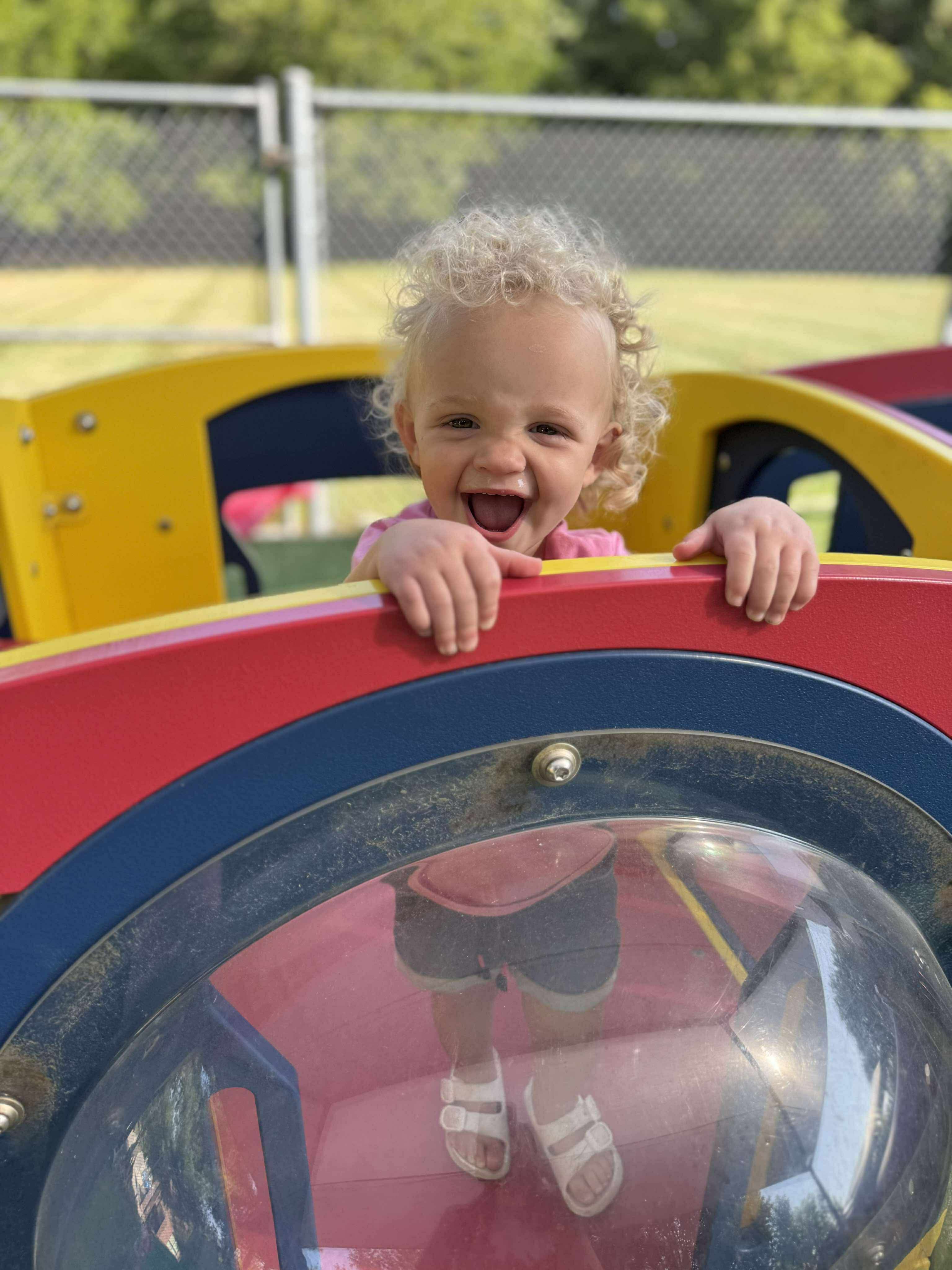 Child smiling and peeking over playground equipment