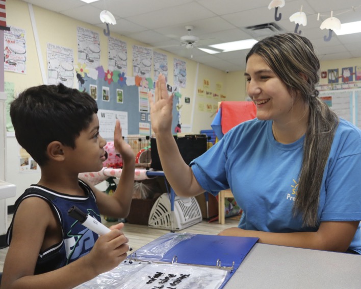 Adult and child high-fiving in a classroom