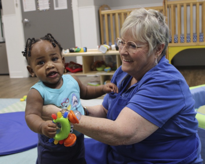Adult and child playing with toy rattle