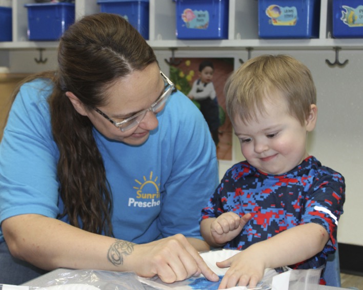 Adult and child looking at something together on a table