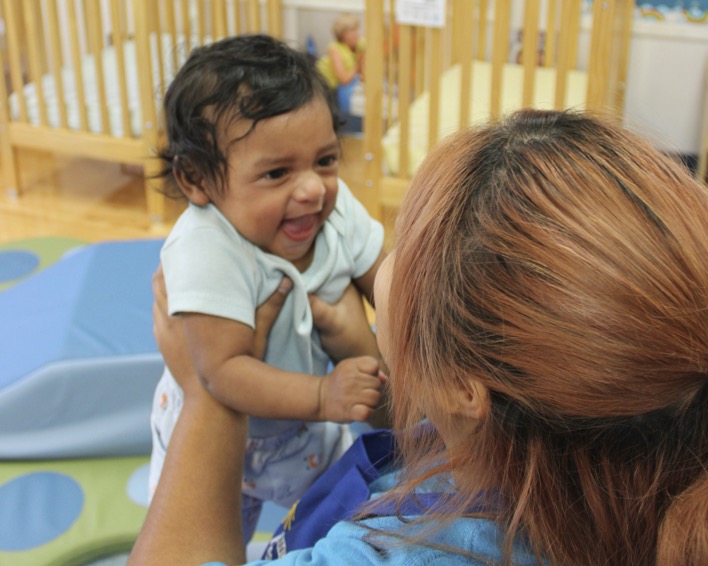 person holding an infant in a room with cribs