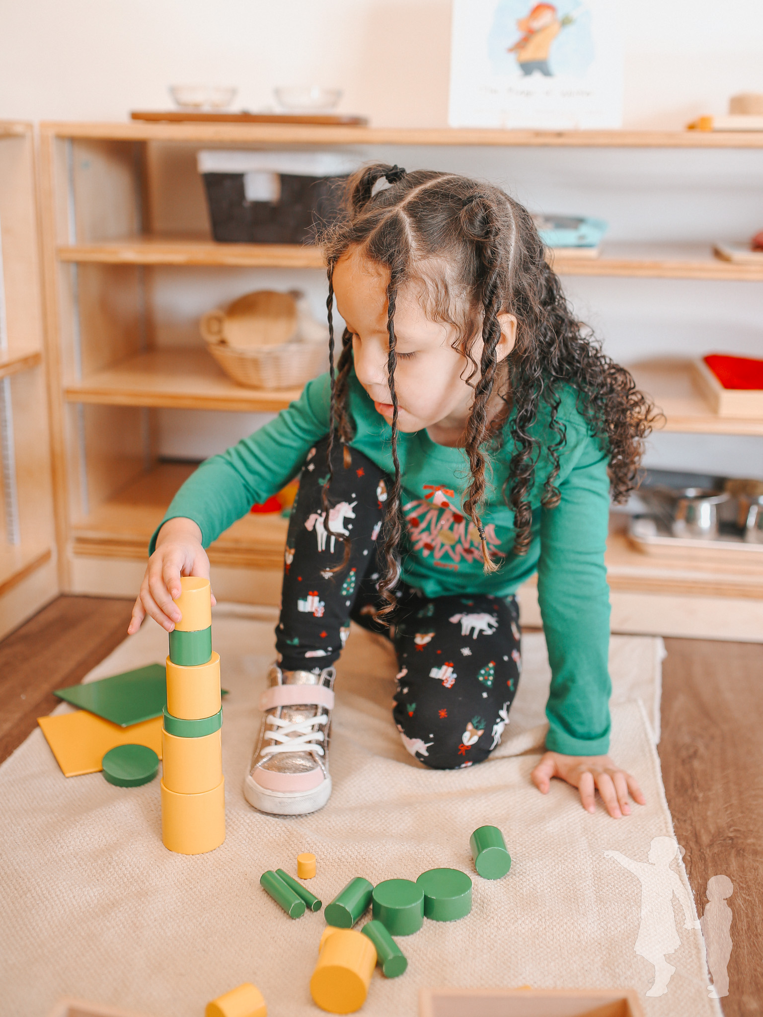Child building with yellow and green blocks on a rug in a classroom