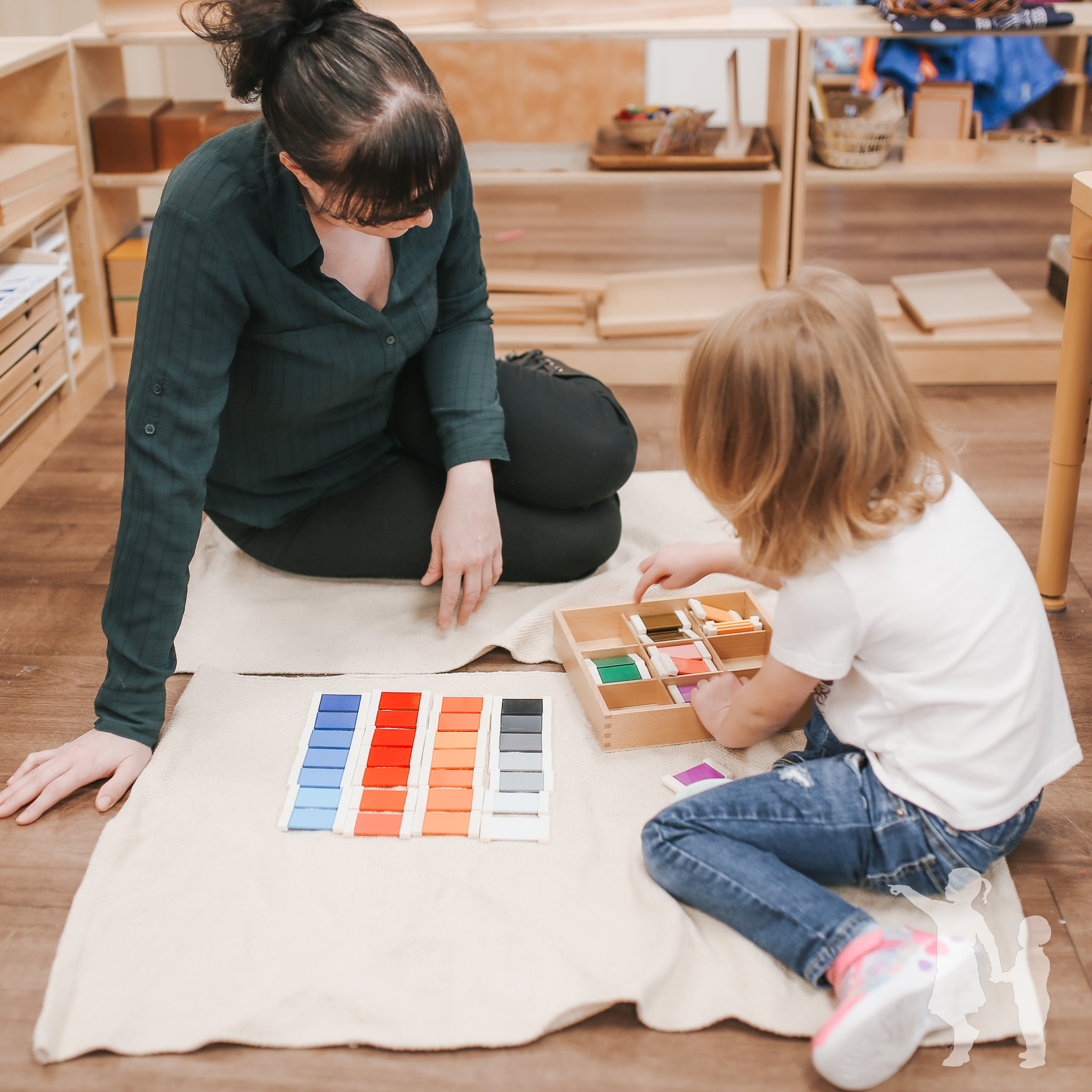 Adult and child playing with color sorting blocks on a mat