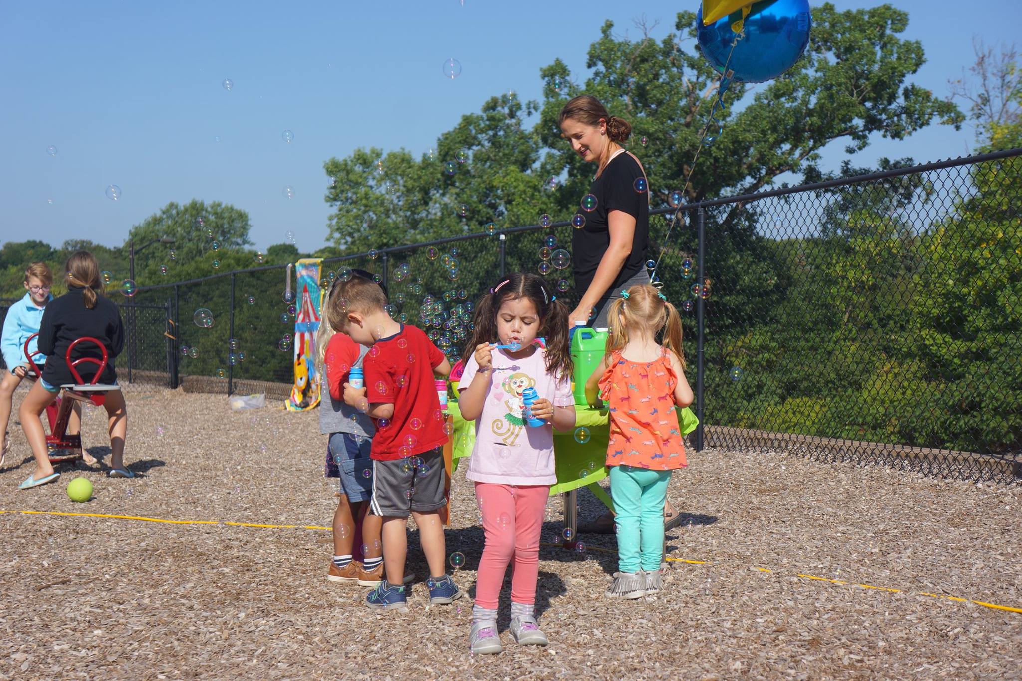 Children blowing bubbles and playing on a wood chip playground