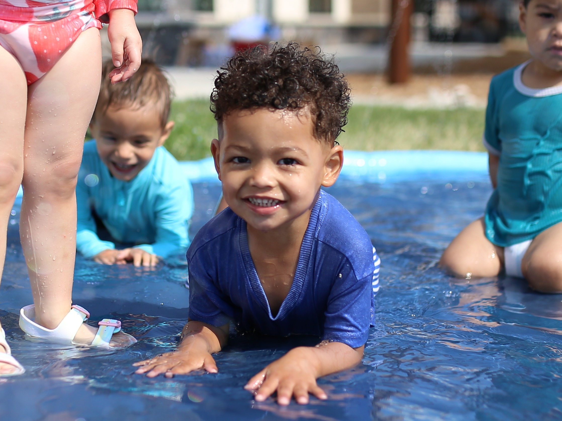 Child smiling while lying on their stomach in a kiddie pool
