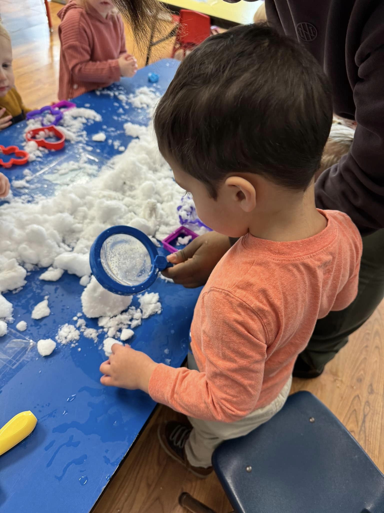 Child playing with artificial snow and a blue magnifying glass
