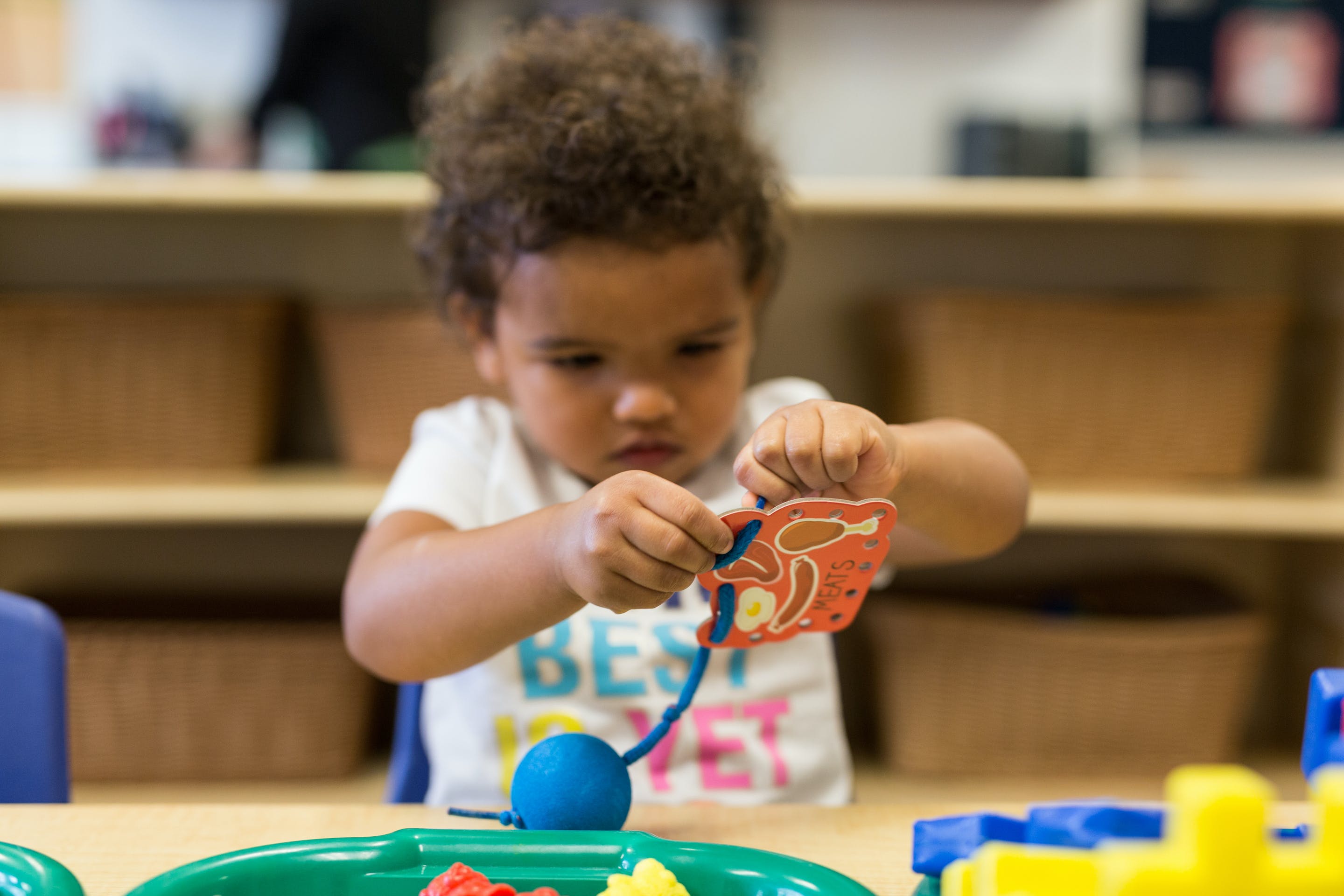 Child playing with a lacing toy at a table