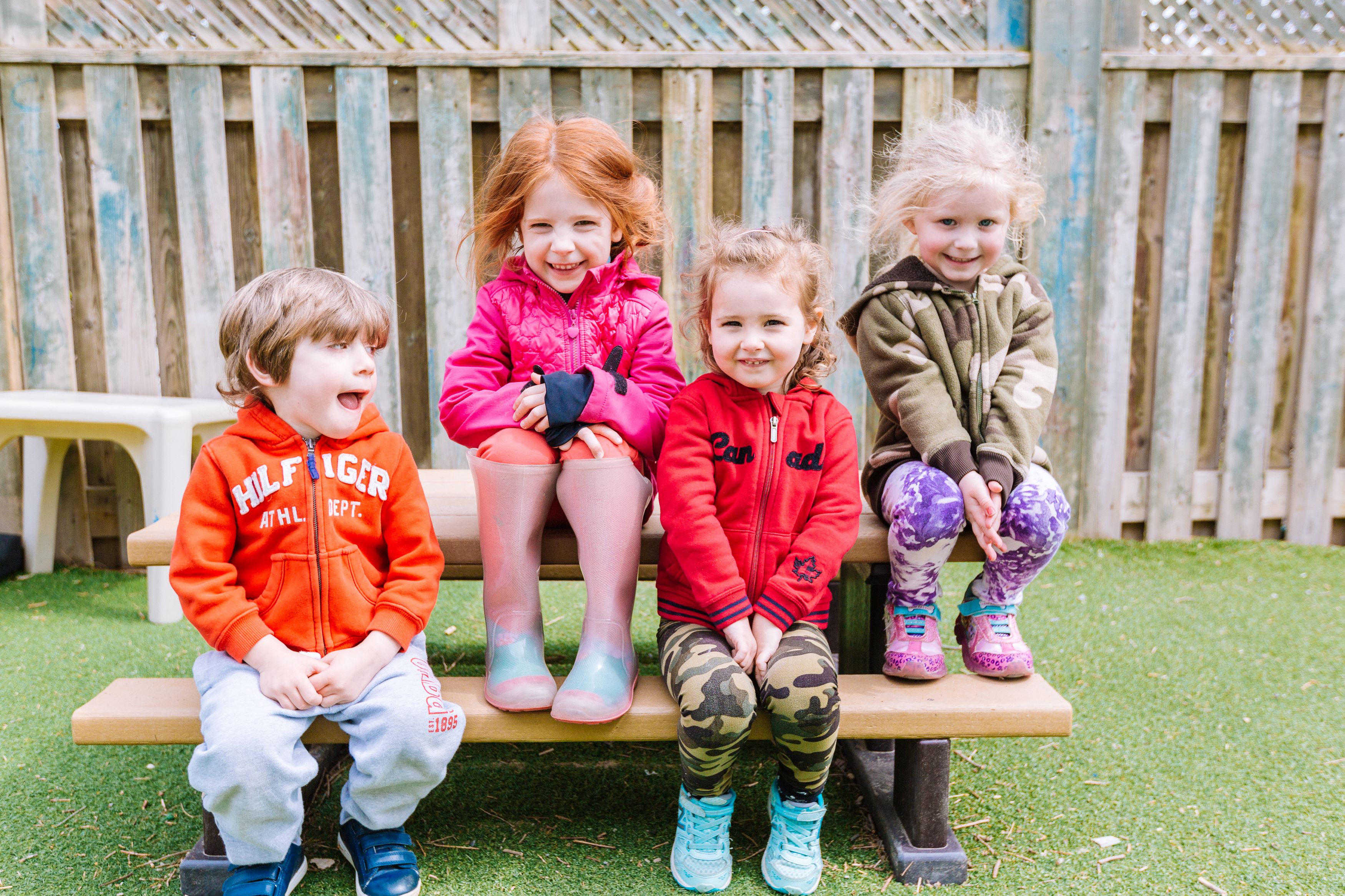 Four children sitting on a bench outdoors