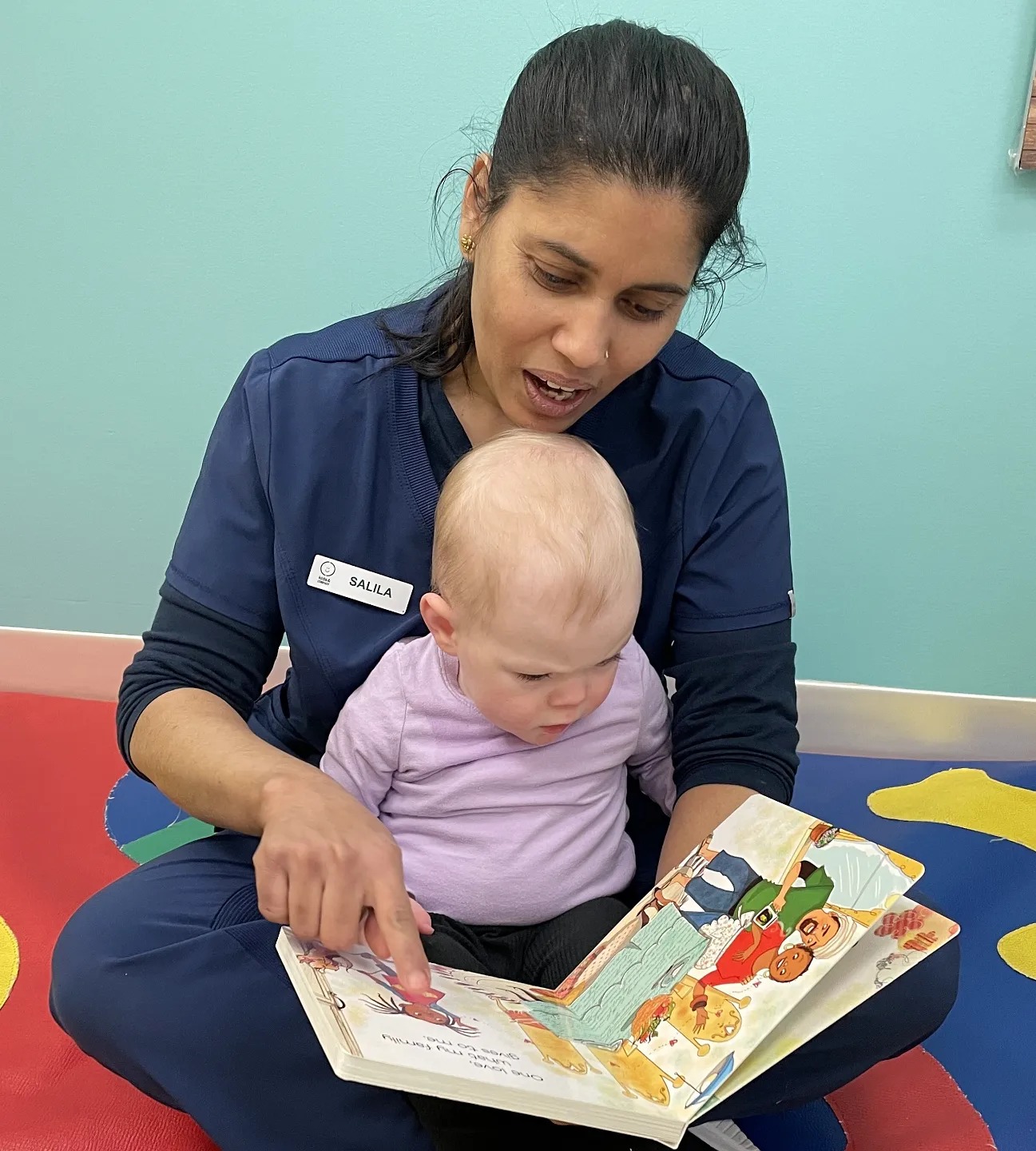 Person and child sitting on floor reading a book