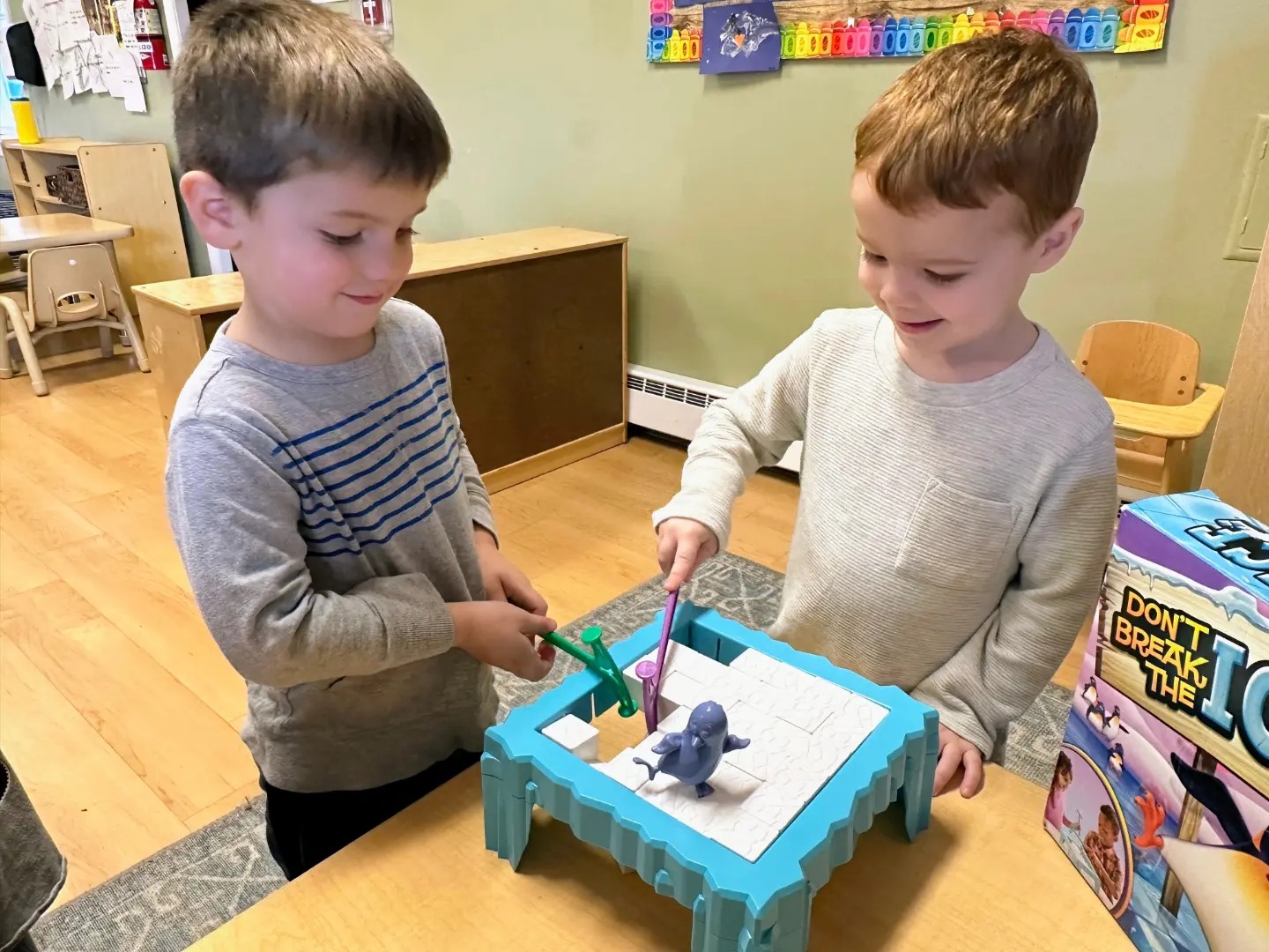Two children playing a game with a blue penguin figure on a table