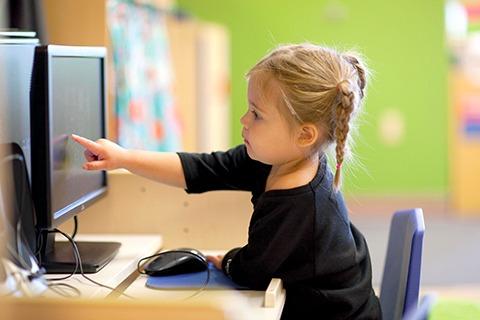 Child pointing at a computer screen